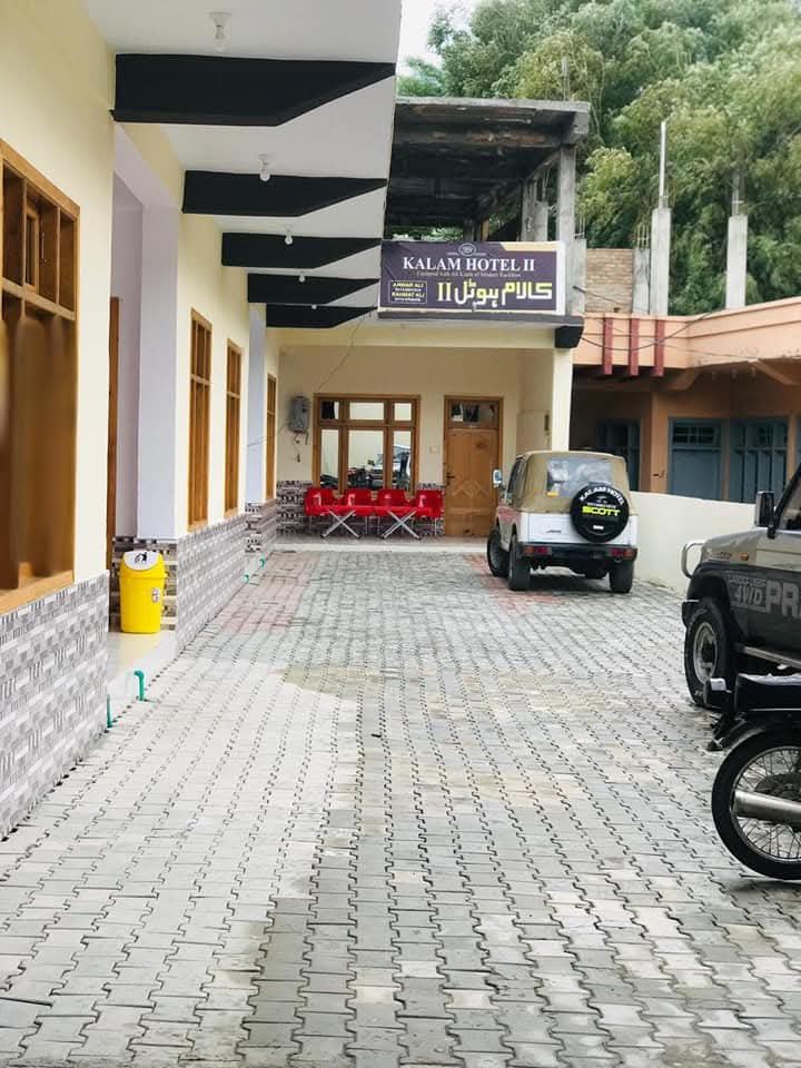 Kalam Hotel entrance with signboard and parked jeeps