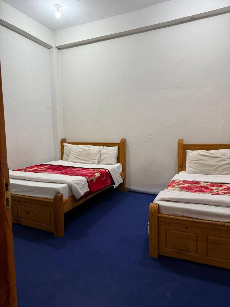 Room with two double beds and blue carpet